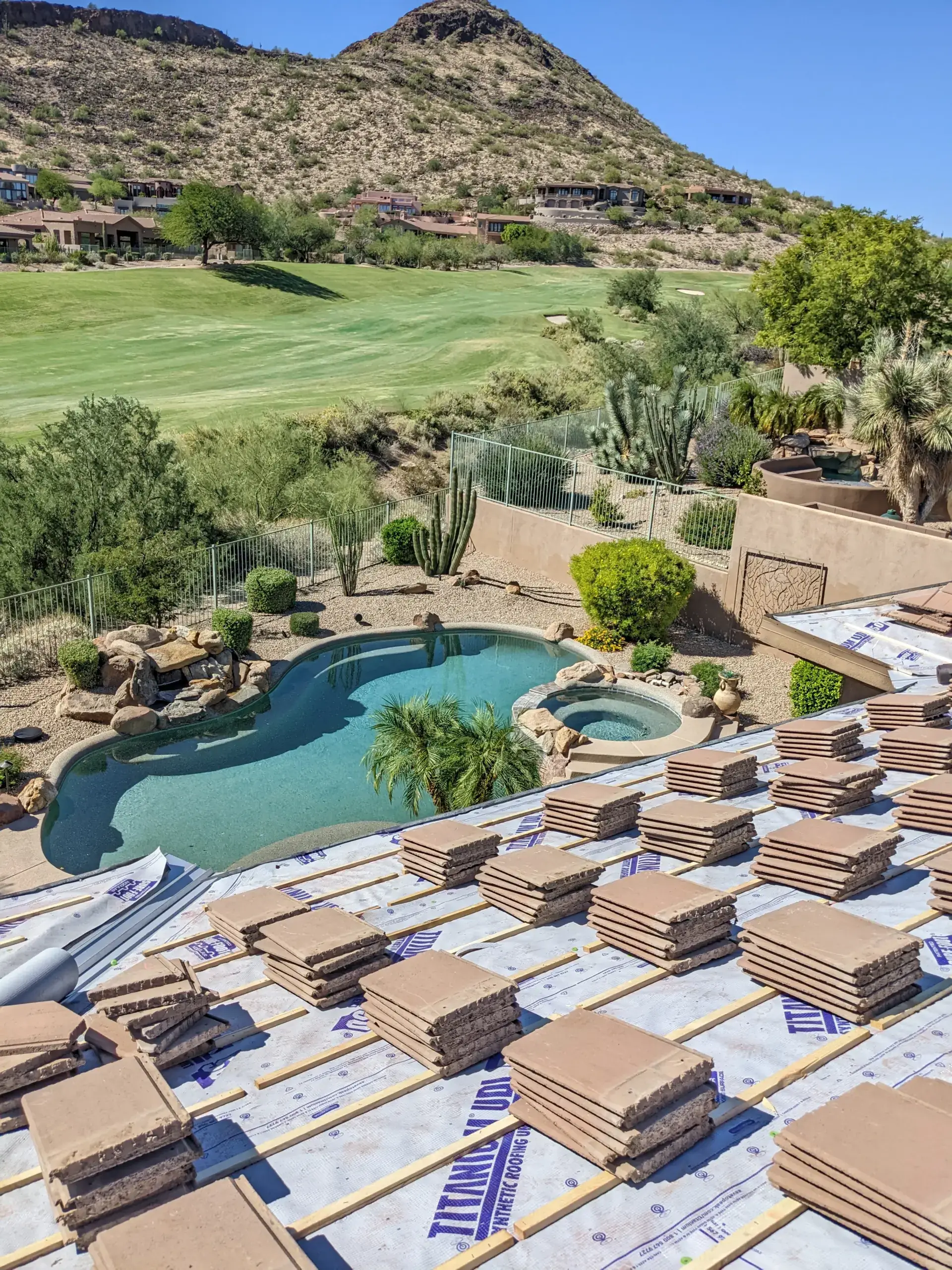 Concrete roof tiles stacked over new underlayment on a home overlooking a golf course and pool