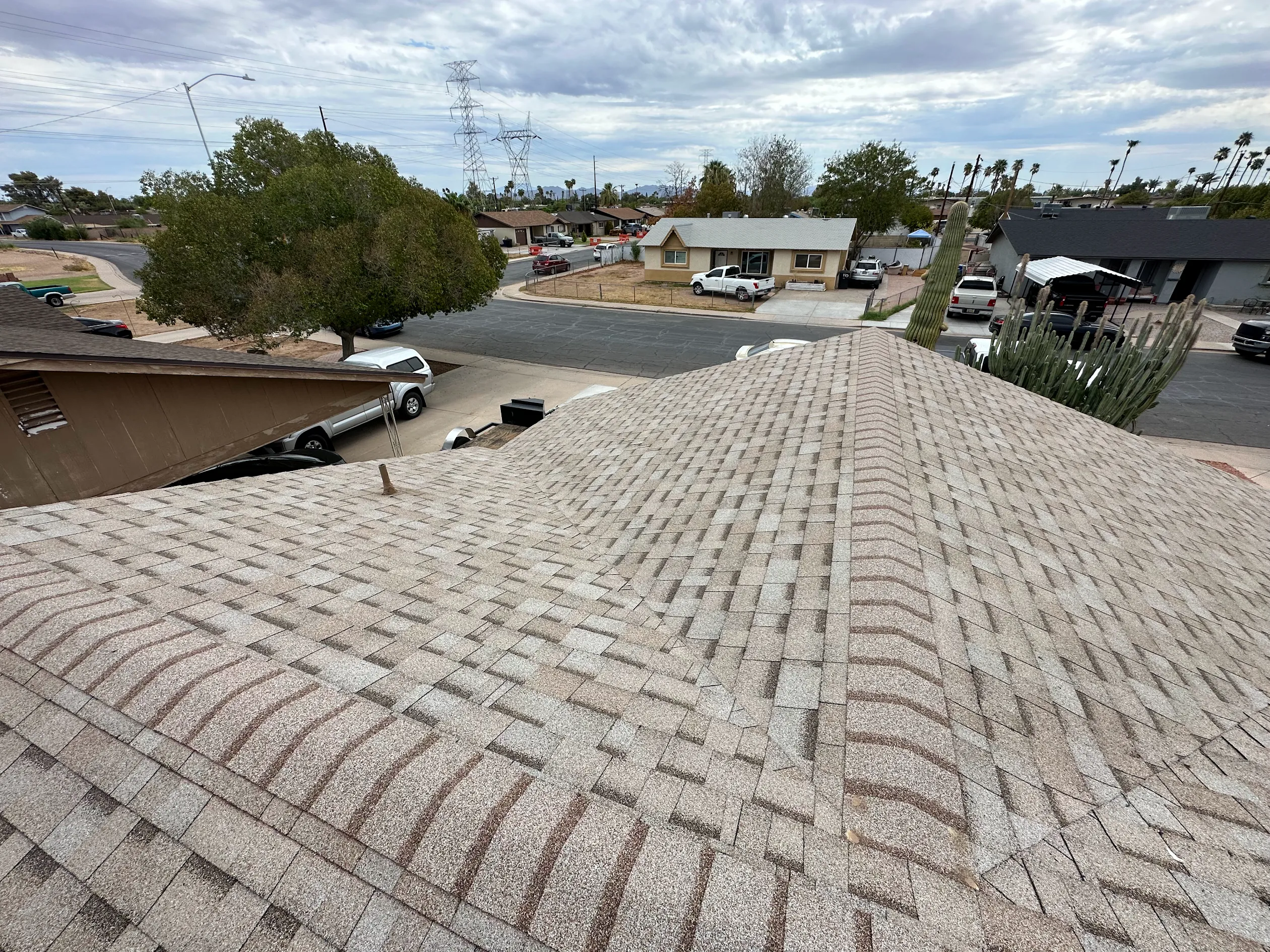 Wide view of a shingle roof with pipe boots and a turbine vent under a cloudy sky